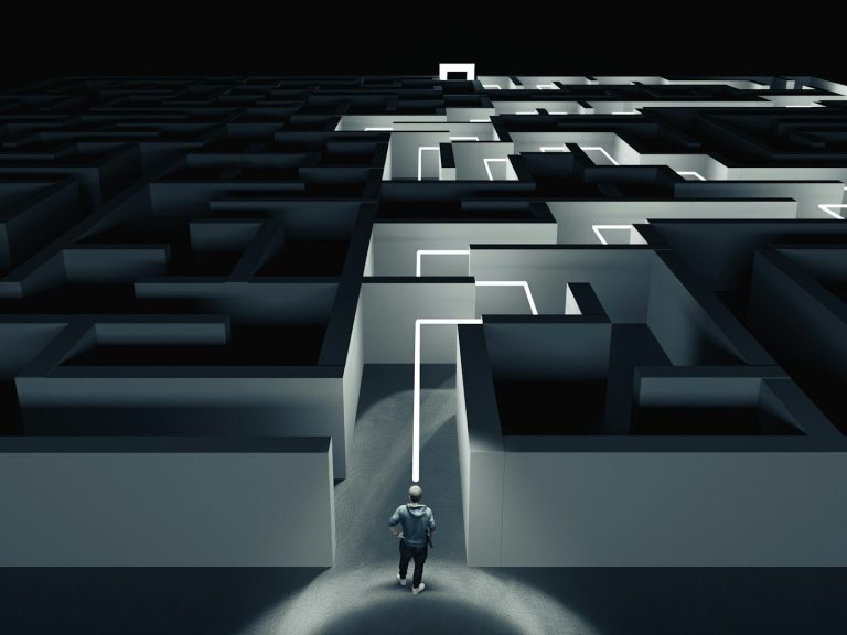 Ein Mensch steht an der Kreuzung eines komplexen, beleuchteten Labyrinths.