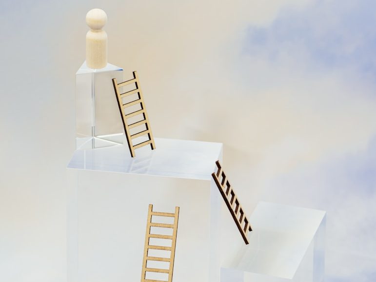 Zwei kleine Leitern führen zu einer Figur auf einer transparenten Plattform.